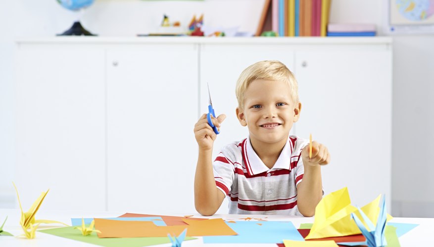 A young boy is learning how to create origami.