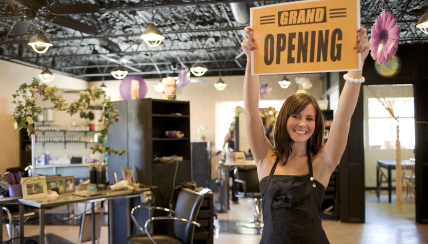 An excited salon owner holds up an open sign.