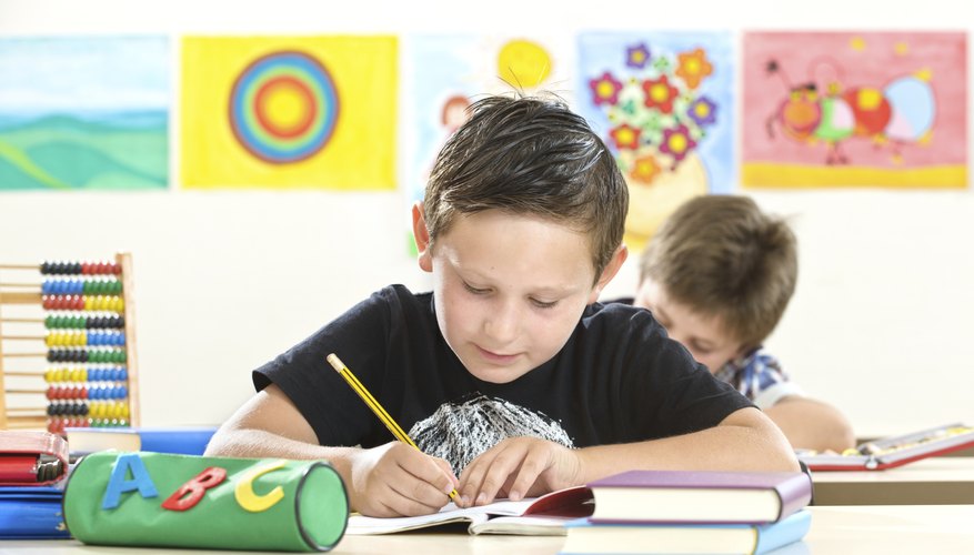A boy is sitting at his school desk.