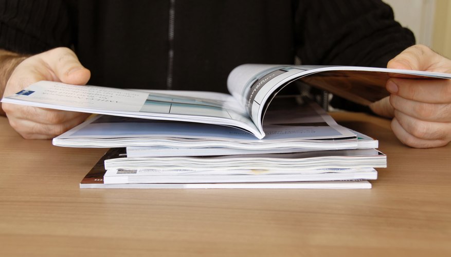 Close-up of man reading research journals.