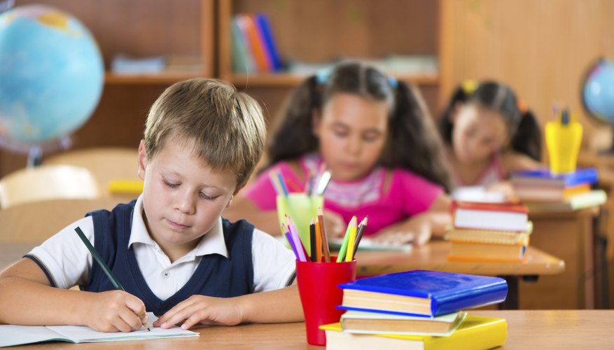 Boy in elementary class writing in notebook.