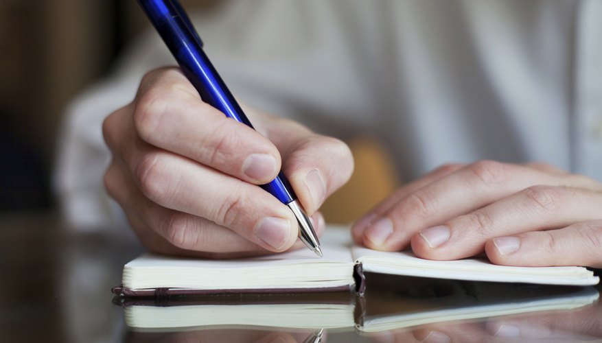 A close-up of a man taking notes during an interview.
