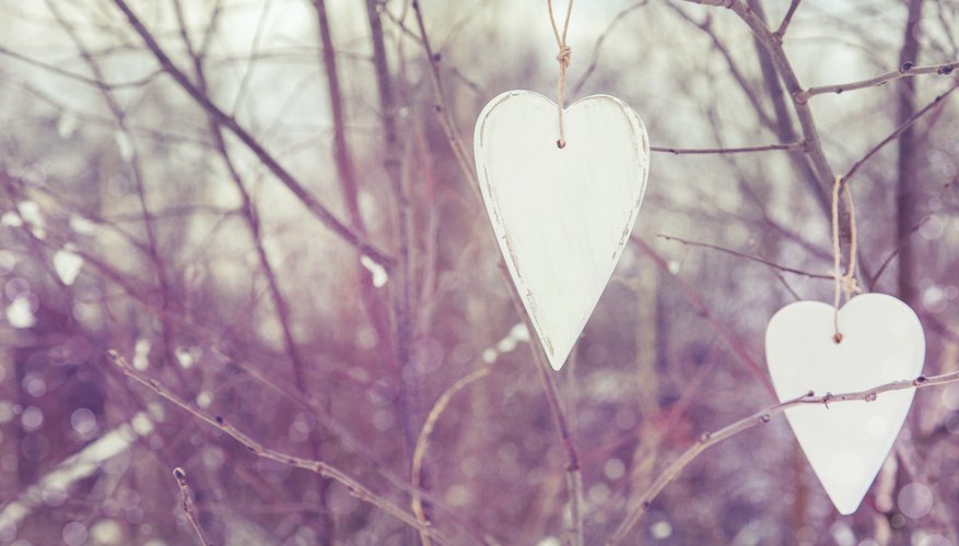 Cut hearts and snowflakes from white plastic containers to hang on trees in the yard.
