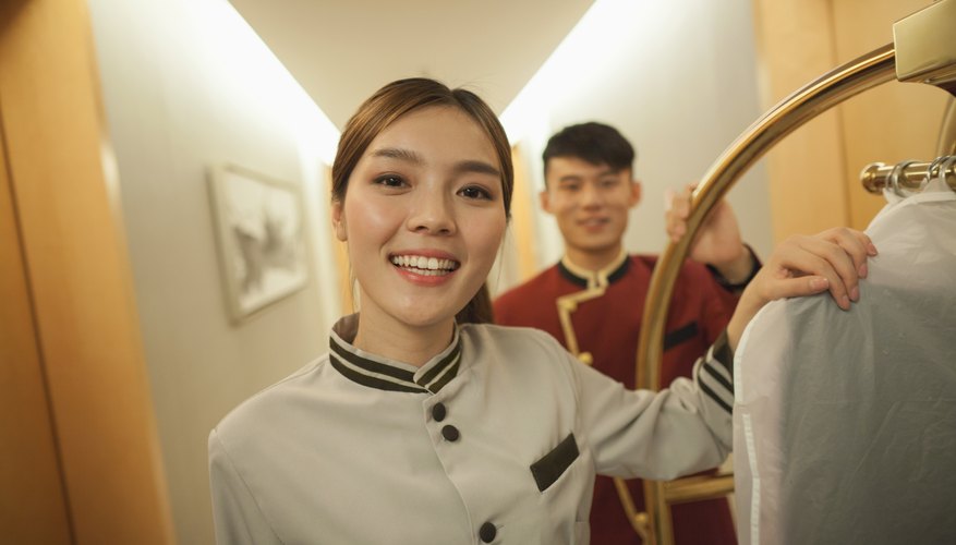 Two young employees smiling in a hotel corridor.