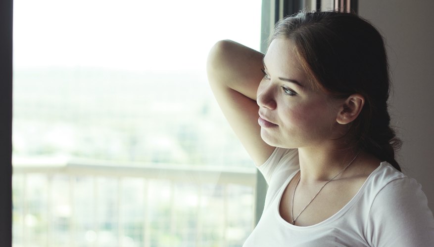 A contemplative woman thinking while looking out of a window.