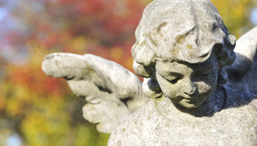 A close-up of a stone statue in a cemetary in autumn.