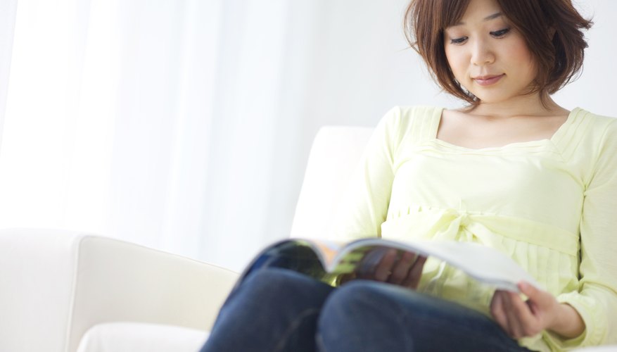 Young woman reading journal on couch.