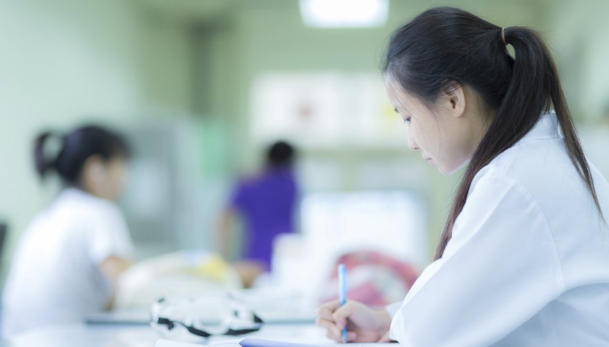 A researcher writing at a table in a laboratory.