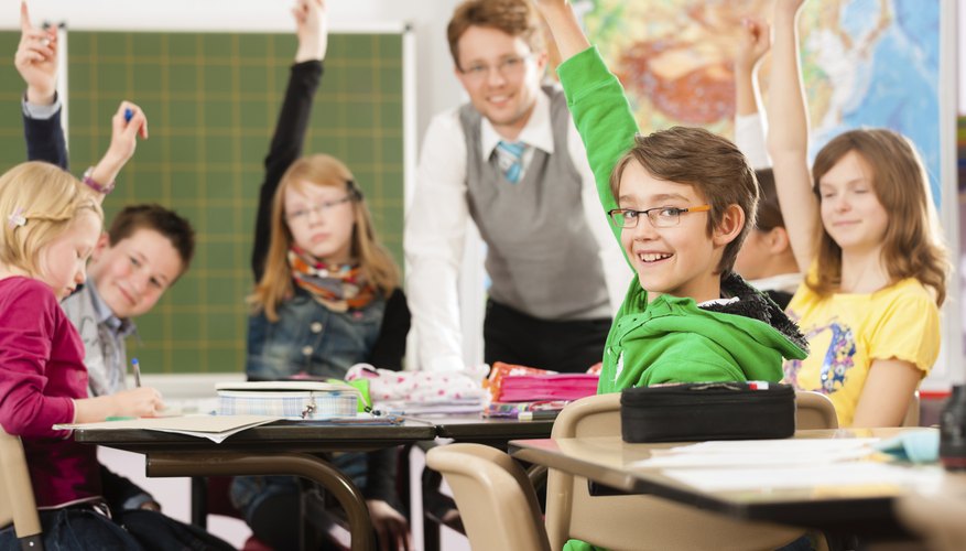Students in a classroom with raised hands.