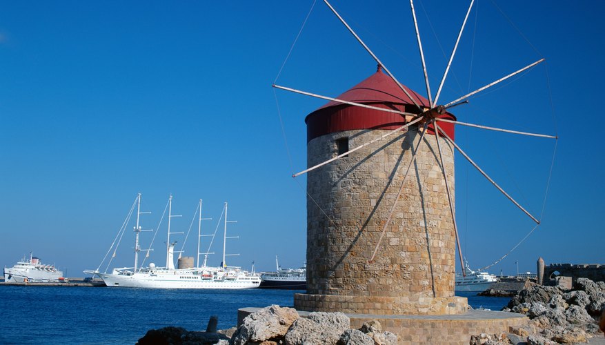 Windmill on coast along water's edge.