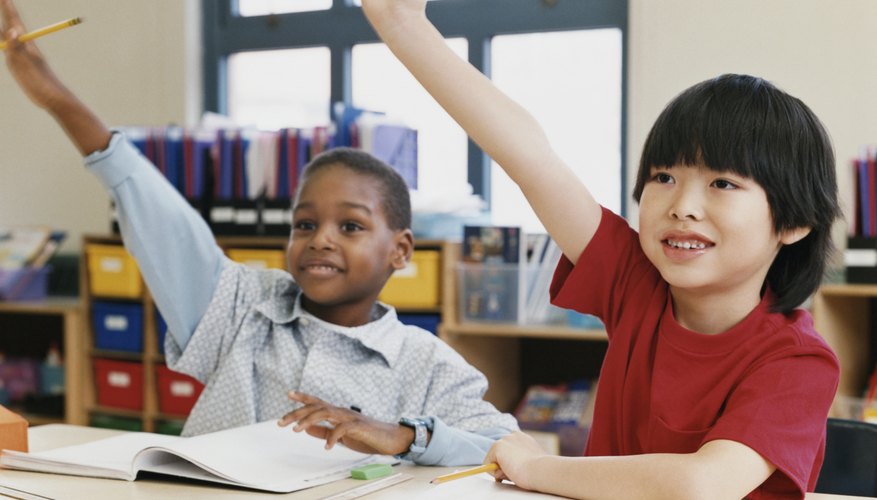 Two school boys raising their hands in class.
