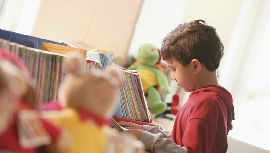 Little boy looking at book in library