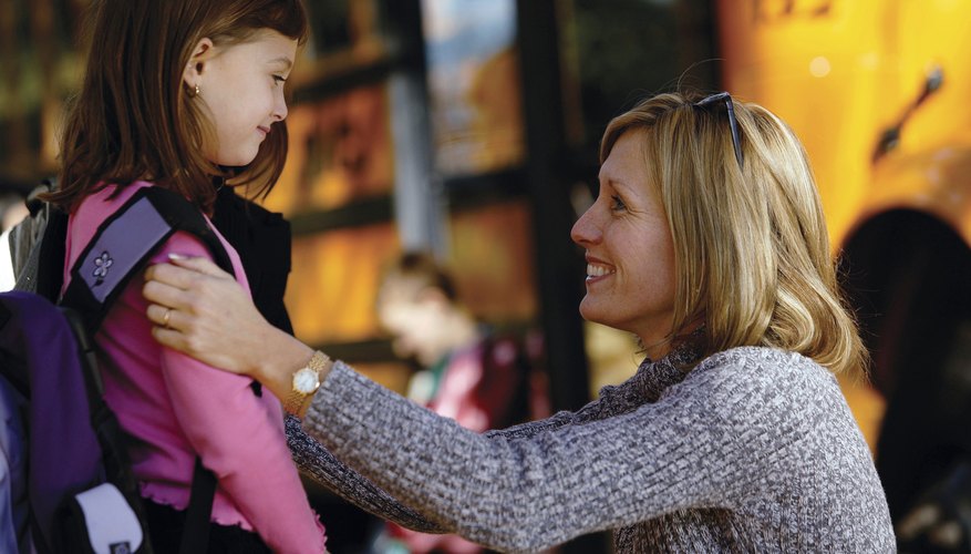Homeroom parent talking with young student outside of the bus.