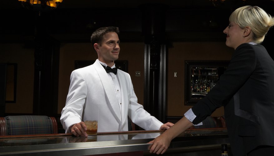 A bartender wears a white tuxedo jacket.