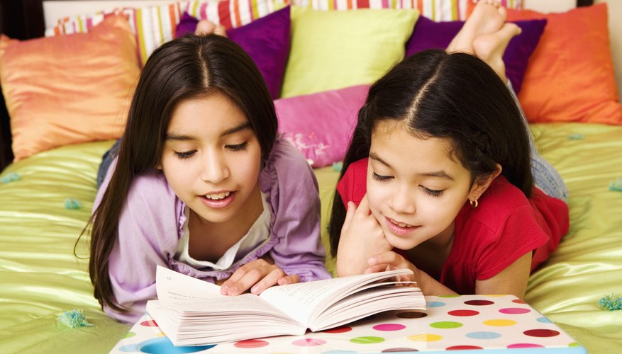 Students reading book on bed.