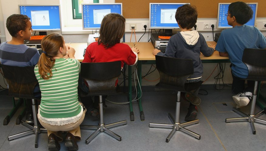 A teacher assists students in a computer lab at school.