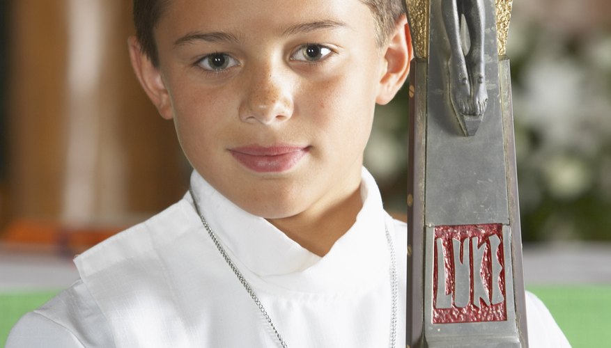 An altar boy carries a large crucifix mounted on a staff as part of a Mass procession.