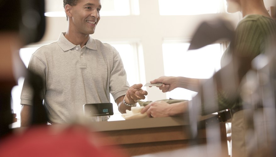 A woman is paying for things at the register with paper money.