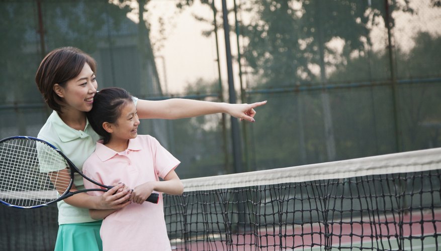 A young girl is learning how to play tennis.