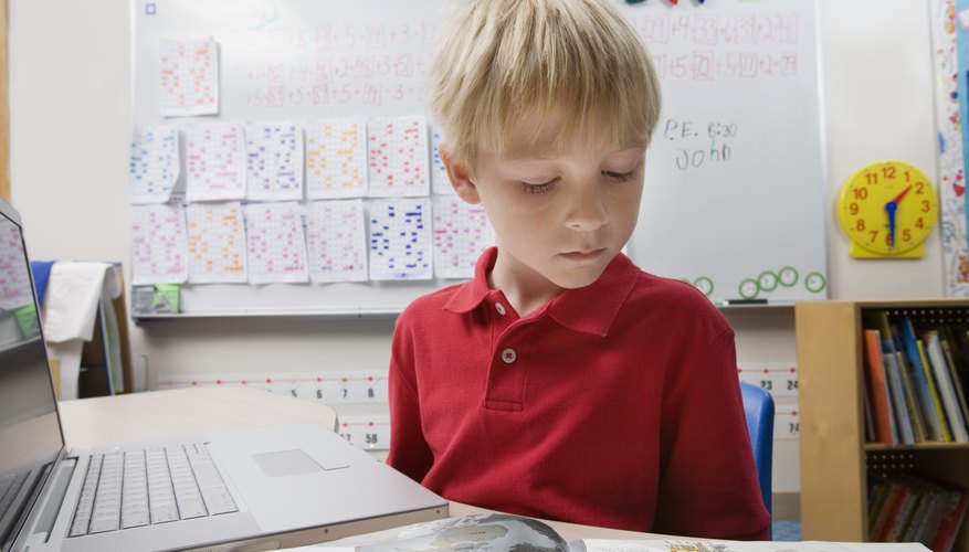 Young boy student reading books and using the internet.
