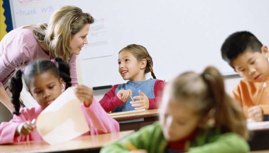 Teacher helping young children with schoolwork in classroom