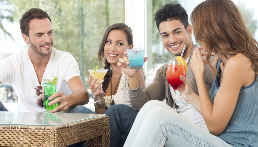 Group of friends drinking tropical drinks around table