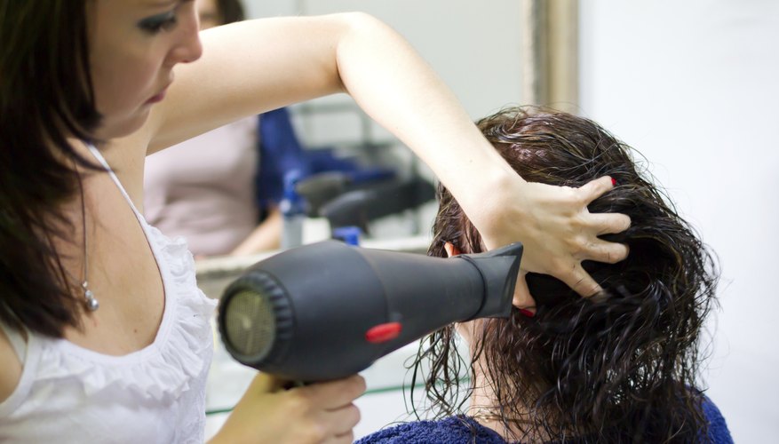 A hairdresser dries a clients hair.