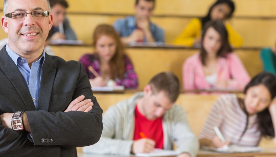A teacher posing in front of students in a lecture hall