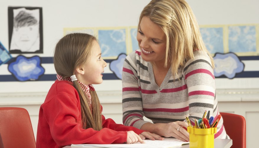 Speech therapist working with young student at desk.