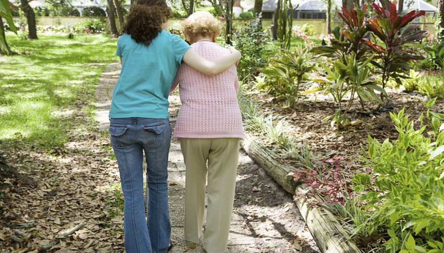 A social worker is walking with an older woman.