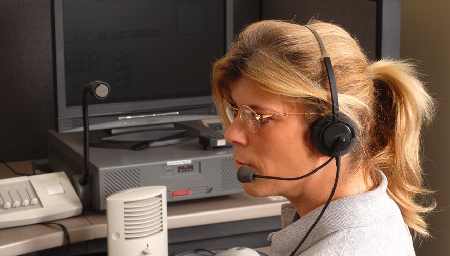 A dispatcher wearing a headset taking a call at a desk.