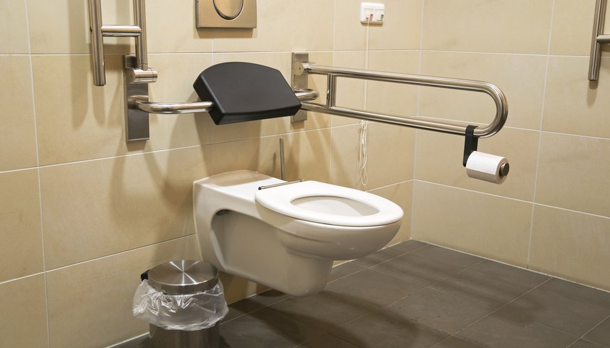 A bathroom with side rails and extended toilet seat.