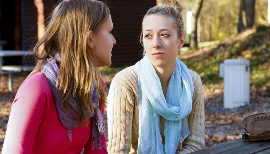 Two friends talking at a picnic table in a park.