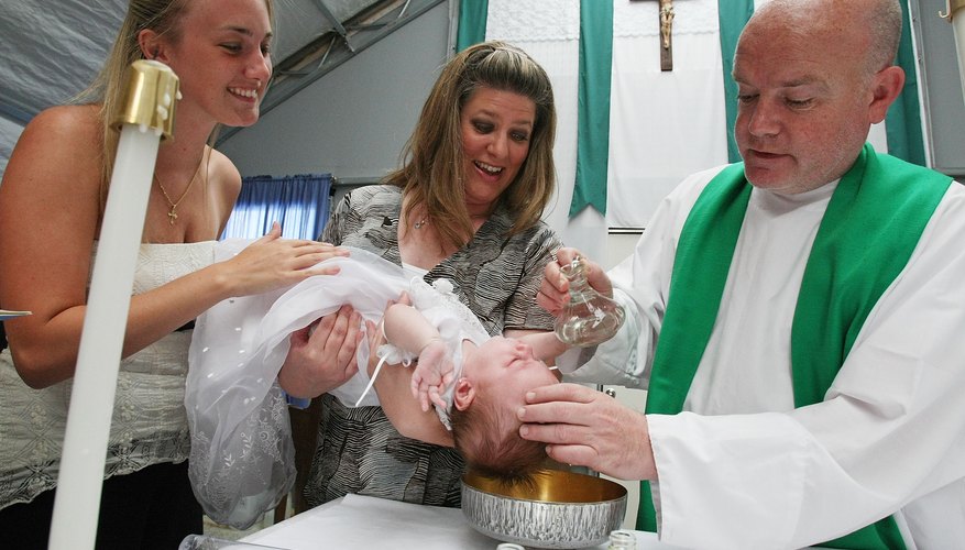 Priest baptise baby as mother and godmother assist in Mississippi.