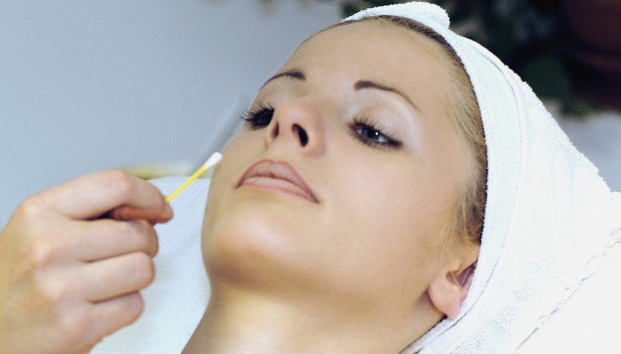 An adult woman is receiving a beauty treatment from a cosmetologist.