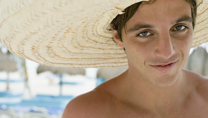 Young man wears straw sombrero at beach