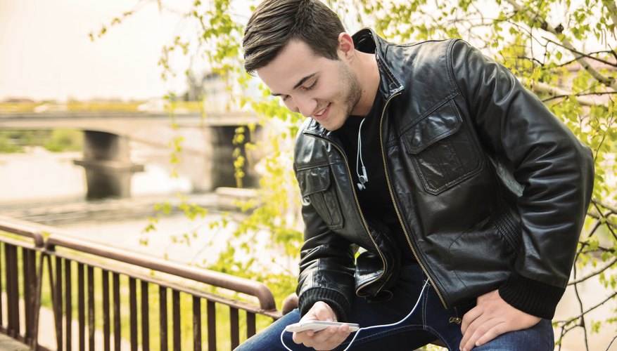 Young man weating a leather jacket, using a smartphone