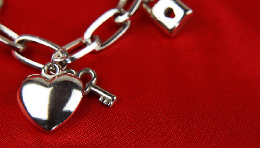 Charms on a charm bracelet, laying on red fabric.
