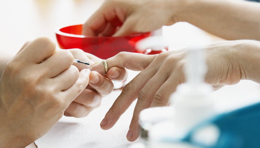 A close-up of a cosmetologist giving a client a manicure.