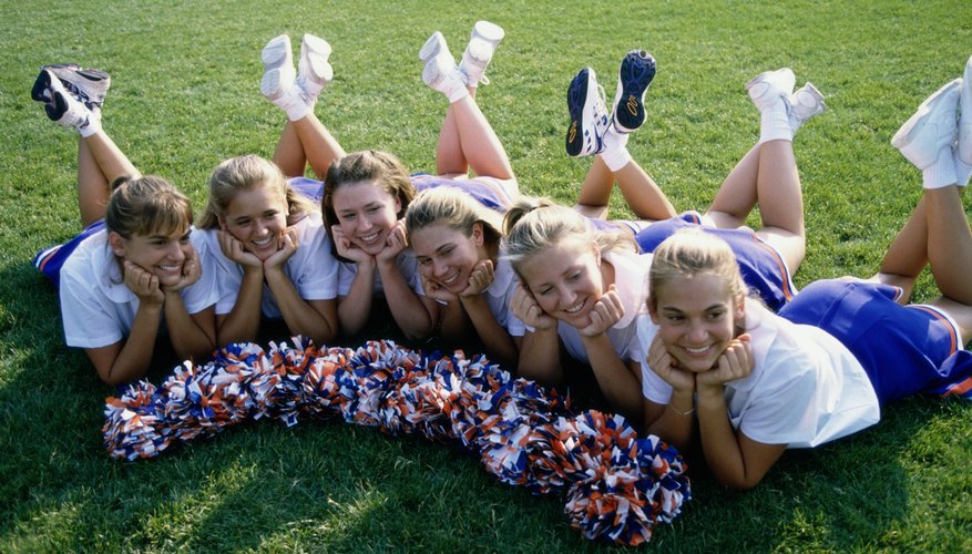 Smiling young cheerleaders on grass.