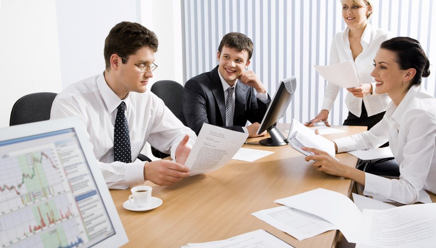 A small group of coworkers sit at one end of a table to discuss a business proposal