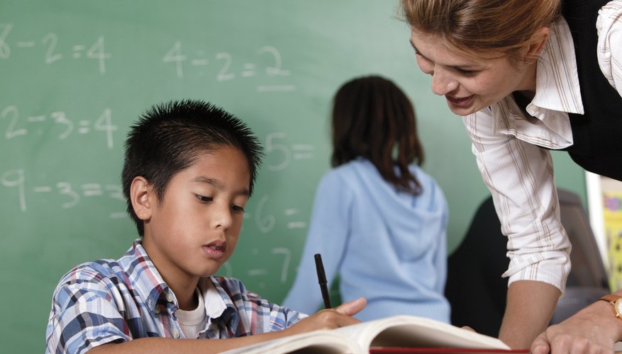 Teacher helping student at desk.