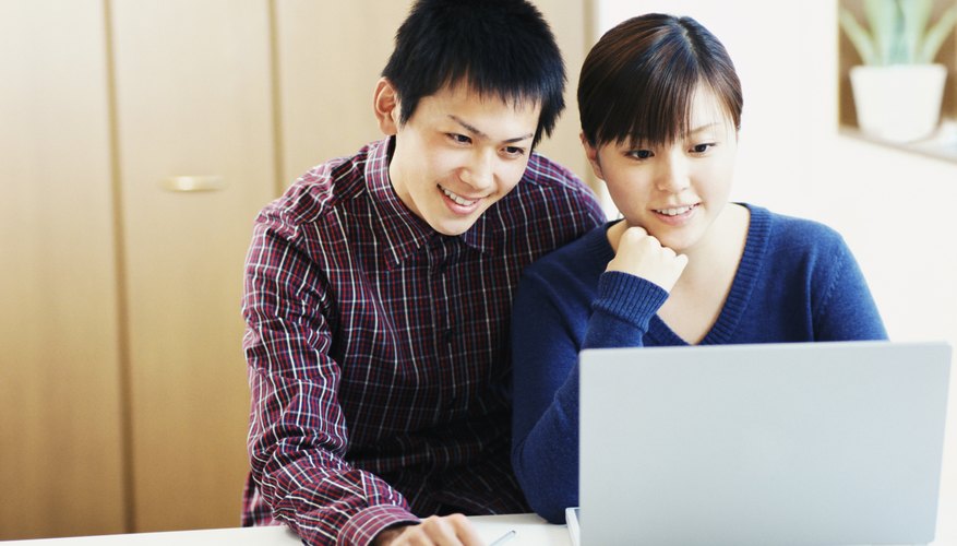 Students reading something together on a laptop.