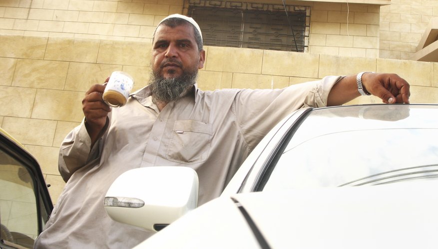 Muslim man standing outside drinking coffee