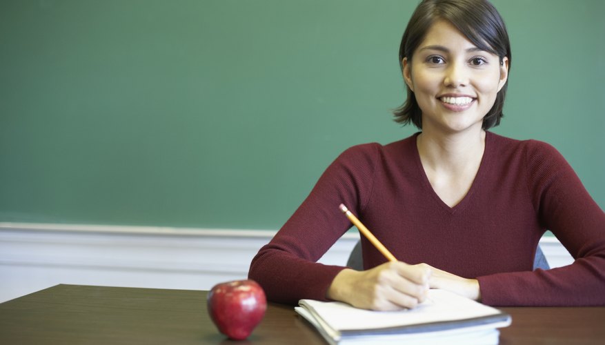 A smiling teacher is at her desk.