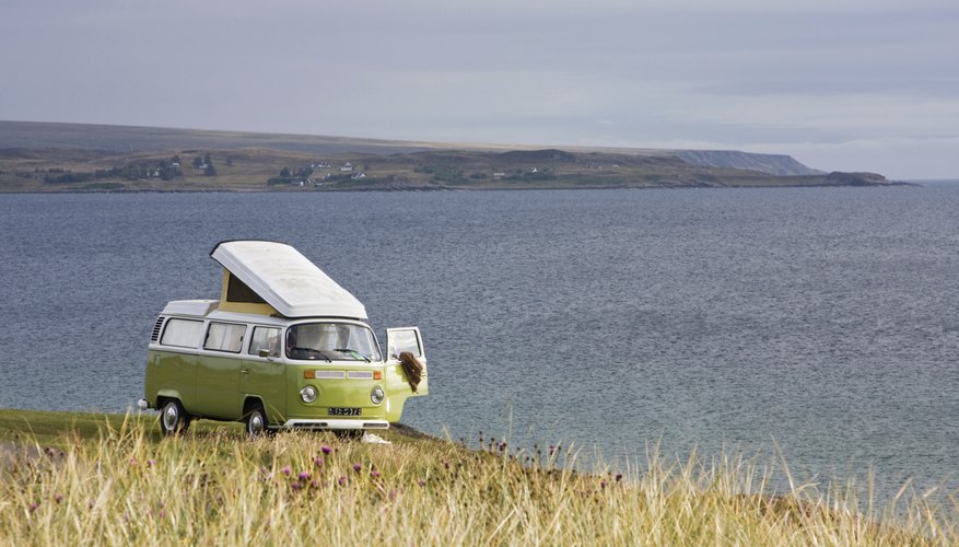 VW bus parked in a field overlooking water.