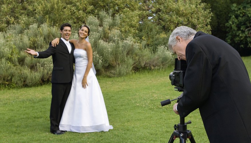 Wedding photographer taking a photo of the bride and groom in a garden.