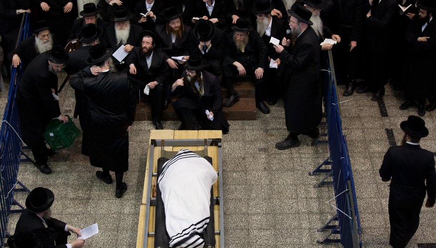 An Orthodox Jew is wrapped in a white linen shroud and tallit.
