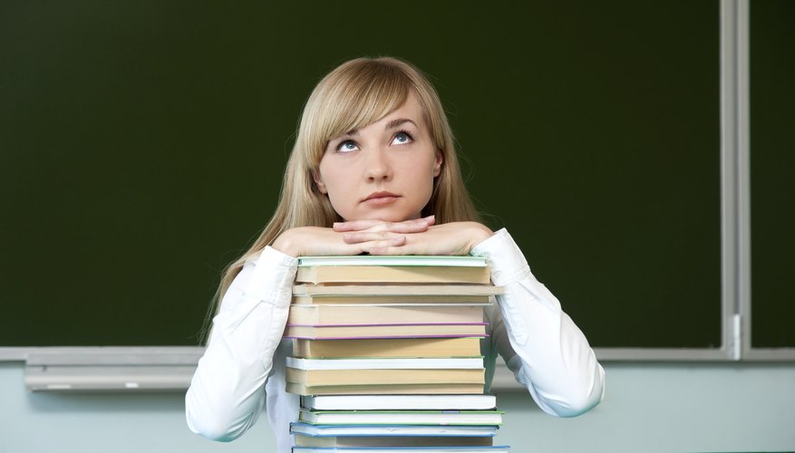 Student thinking on top of stack of books