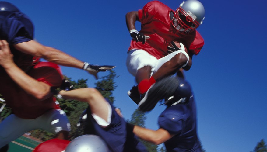 A football player jumps over a crouching player of the opposite team